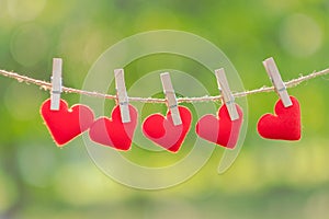 Red heart shape decoration hanging on line with copy space for text on green nature background. Love, Wedding Romantic and Happy