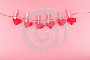 Red heart shape decoration hanging on line with copy space for text on pink background. Love, Wedding, Romantic and Happy