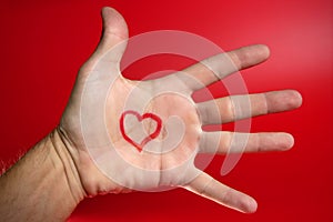 Red heart shape drawed on a male human hand