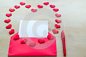 Red heart shape with envelope and pen on wooden background