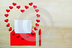 Red heart shape with envelope and pen on wooden background