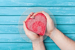 Red heart shape in hands top view. Healthy, donation organ, donor, hope and cardiology concept. Valentines day card.