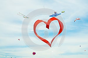Red heart shape kite is flying in blue sky