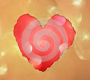 Red heart shape made from torn paper over glitter boke soft lights.