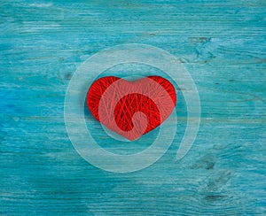 Red heart shape made from wool on blue wooden background