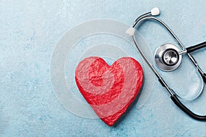 Red heart shape and medical stethoscope on blue background top view. Health care, medicare and cardiology concept. photo