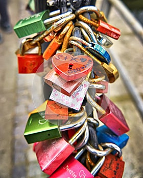 The red heart shape padlock hanging in the middle of many blurred love padlocks. Concept padlocks love forever. Valentine