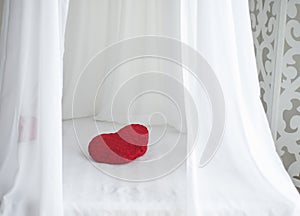 Red heart shape pillow on white bed sheet