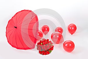 Red heart shape umbrella, roses and balloons against a white background