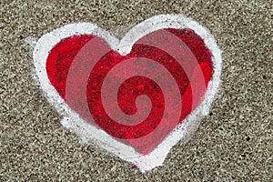 Red heart shape with white outline painted sprayed on massive concrete wall.