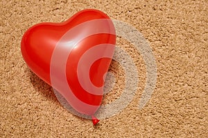 Red heart-shaped balloon on beige carpet. Valentines day concept