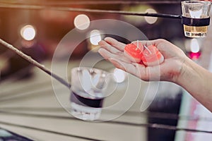 A red heart shaped candle in a woman`s hand with candlelight in many small glass cups.