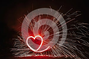 Red heart shaped firework with sparkles on black background in n