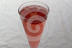 Red, heart shaped ice cubes float on top of pink champagne