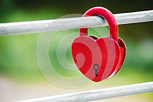 A Red heart shaped lock as a symbol of love. Padlock heart on a green background.