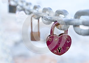 A red heart-shaped lock hangs from the bridge chain. The wedding custom is a symbol of eternal love.