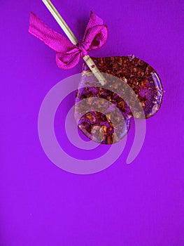 Red heart-shaped lollypop shot over purple background, minimalist concept for Valentines Day, Mothers Day. Love creative hearts