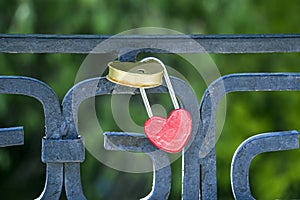 Red Heart shaped love lock hanging on bridge. Valentine`s Day concept. Eternal love symbol