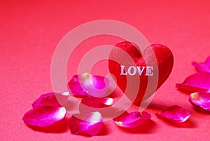 A red heart shaped with Love and Rose petals on red background