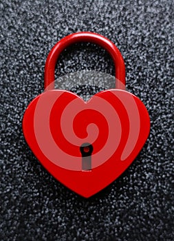 Red heart shaped padlock on black glitter background.