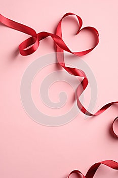 Red Heart shaped ribbon on pink background. Happy Valentine`s Day or Mother`s Day concept