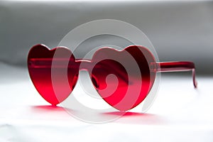 Red heart shaped sunglasses on light background, closeup