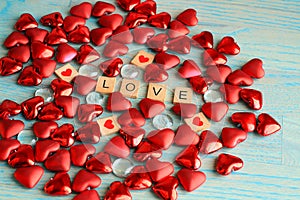 Red heart shapes and word love on wooden background