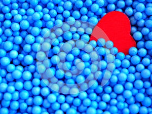 Red heart on small blue foam balls background.
