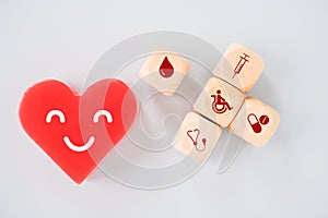 Red heart with smiling face and health and medical sign on wood cubes, for health insurance, wellness, wellbeing concept
