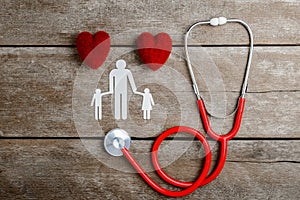 Red heart, stethoscope and paper chain family on wooden table