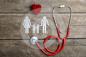 Red heart, stethoscope and paper chain family on wooden table