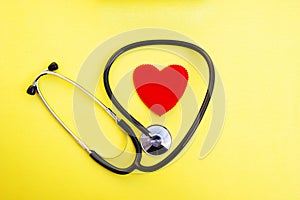Red heart and stethoscope on yellow background, heart health care and medical technology concept, selective focus,