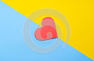 Red heart symbol on yellow-blue paper background