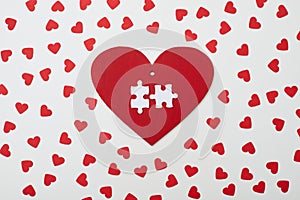 Red heart with two white puzzle encircled with small hearts