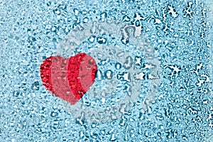 Red heart under water drops on glass on blue background with copy space