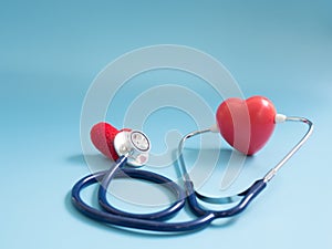 Red heart using deep blue stethoscope on the blue background for hear their other heart. Concept of love and caring patient by the