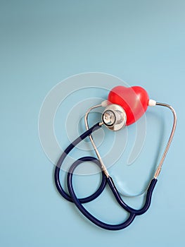 Red heart using deep blue stethoscope on the blue background for hear their own heart. Concept of love and caring patient by the h