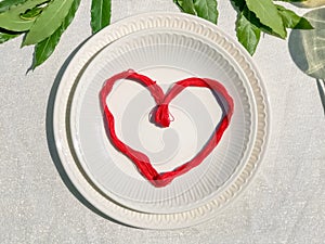 Red heart on white empty plate top-view close-up. Love concept. St. Valentine`s Day. Love proposal. Engagement. Restaurant.