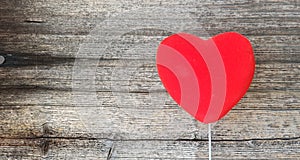 Red Heart on a White Handle in front of Old Grunge Wooden Table