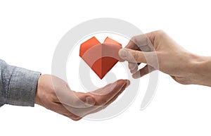 Red heart in woman and man hands. Image on isolated white background.