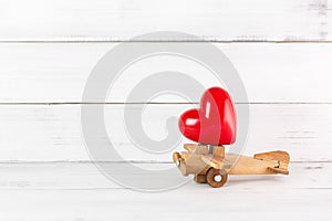 Red Heart on Wooden Toy Plane over white wood background.  Fly to love concept with copy space