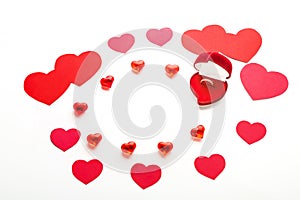 Red hearts of different sizes for Valentine`s day and glass hearts and a velvet heart-shaped box with a ring on a white backgroun