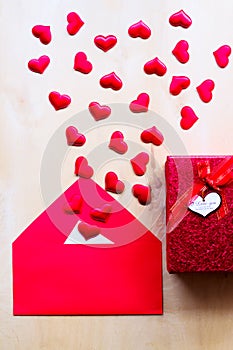 Red hearts with envelope and gift box on wooden background