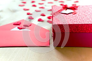 Red hearts with envelope and gift box on wooden background