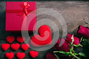 Red hearts, flower roses and gift box on wooden background