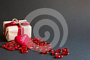 Red hearts and a gift box on a black background - Valentine`s day holiday, banner, copyspace. Shopping for a loved one, a couple