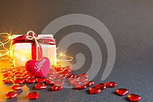 Red hearts and a gift box on a black background - Valentine`s day holiday, banner, copyspace. Shopping for a loved one, a couple