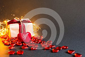 Red hearts and a gift box on a black background - Valentine`s day holiday, banner, copyspace. Shopping for a loved one, a couple