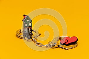 Red hearts and a house in handcuffs on a yellow background.