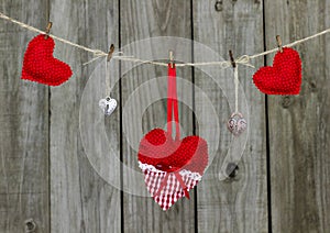 Red hearts and locks hanging from clothesline by rustic wooden fence